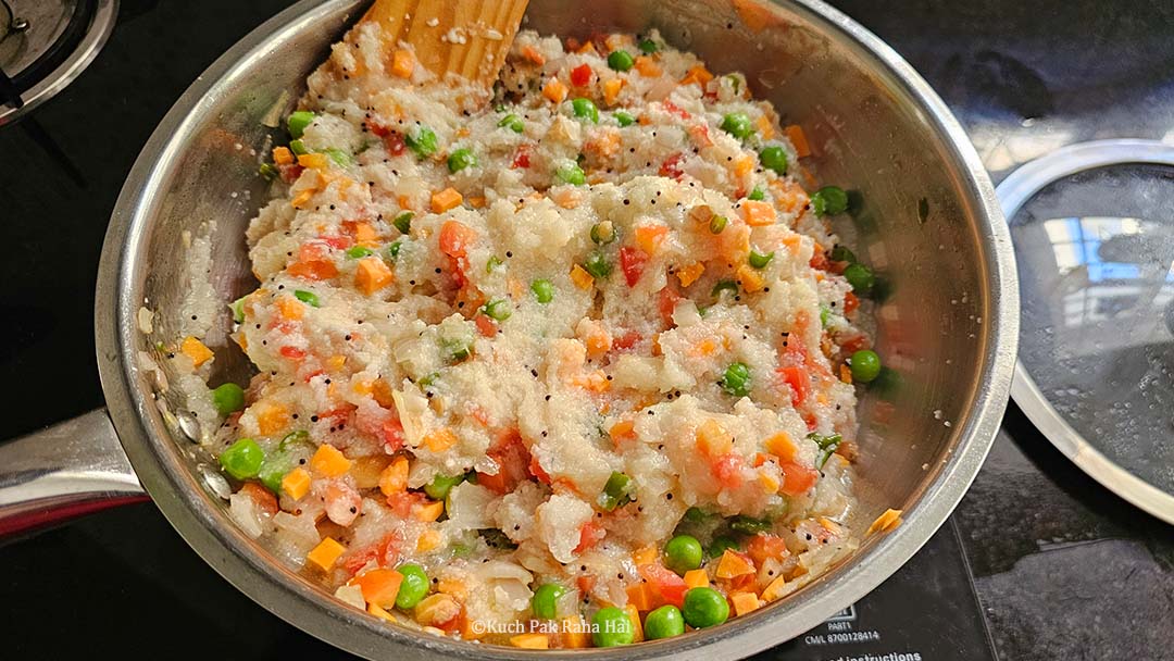 Adding ghee and coriander to upma.