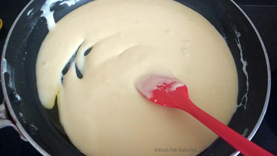 Cooking peda mixture in a pan on stovetop.