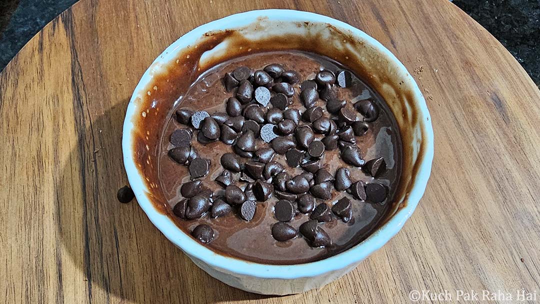 Adding chocolate chips to the top of mug cake.