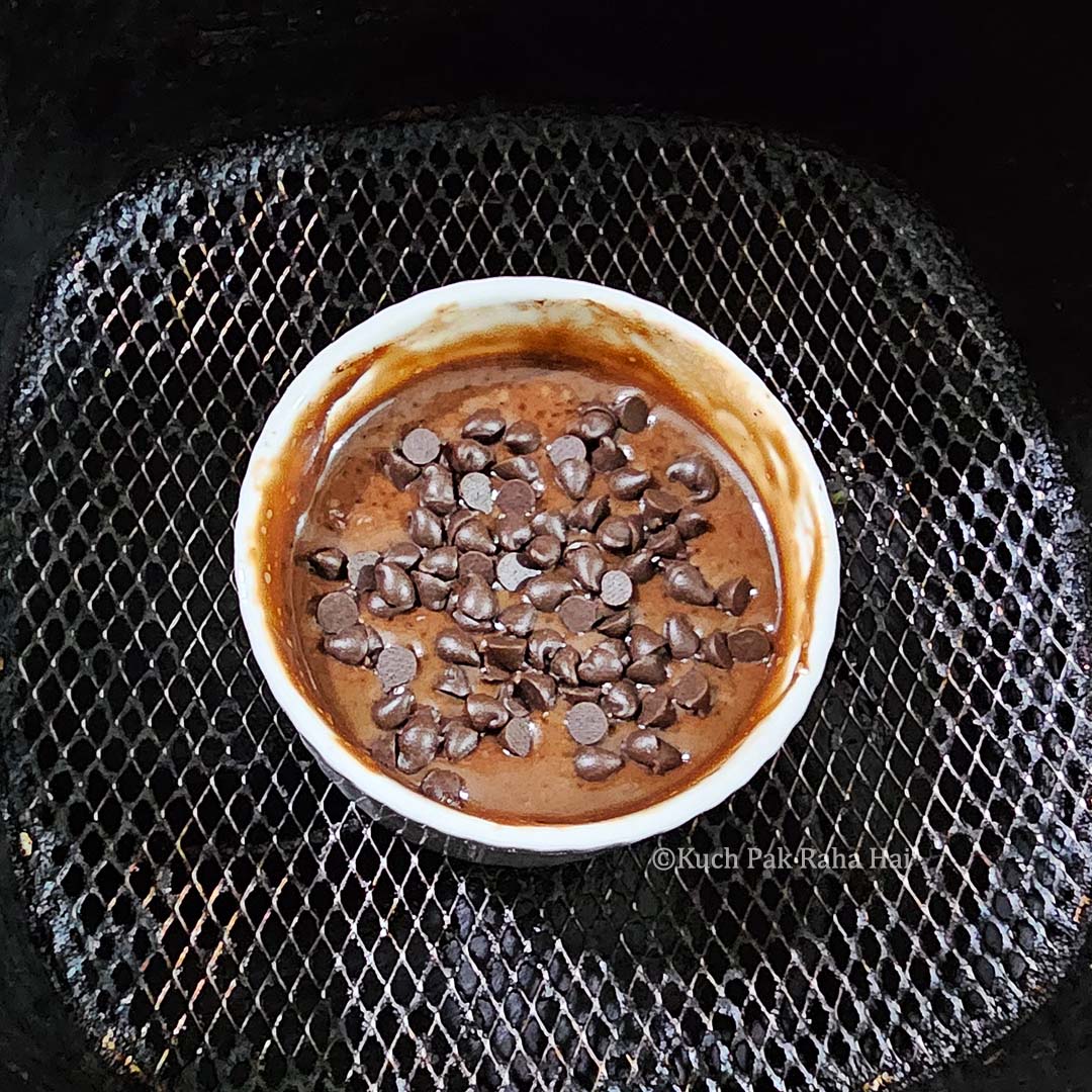 Placing batter filled mug in air fryer.