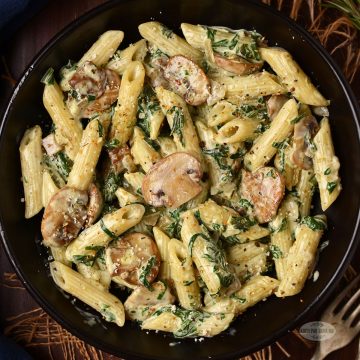 Creamy mushroom and spinach pasta served in a bowl.