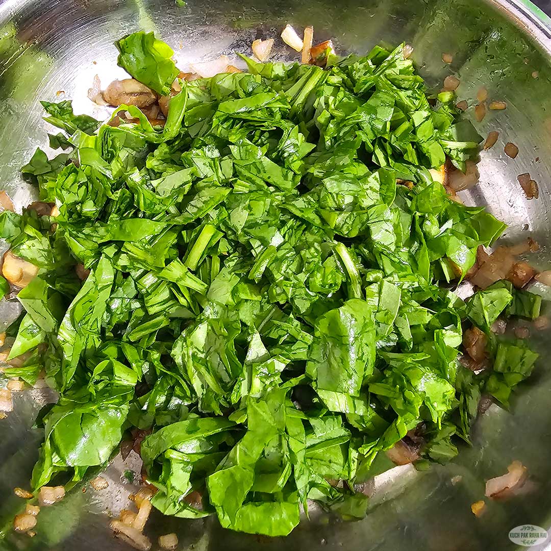 Adding spinach to cooked mushrooms.