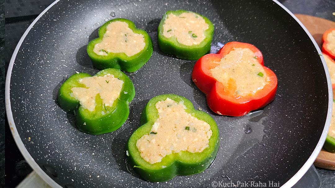 Transferring stuffed capsicum in a pan.