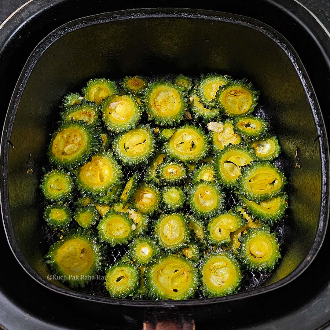 Transferring karela slices in air fryer.