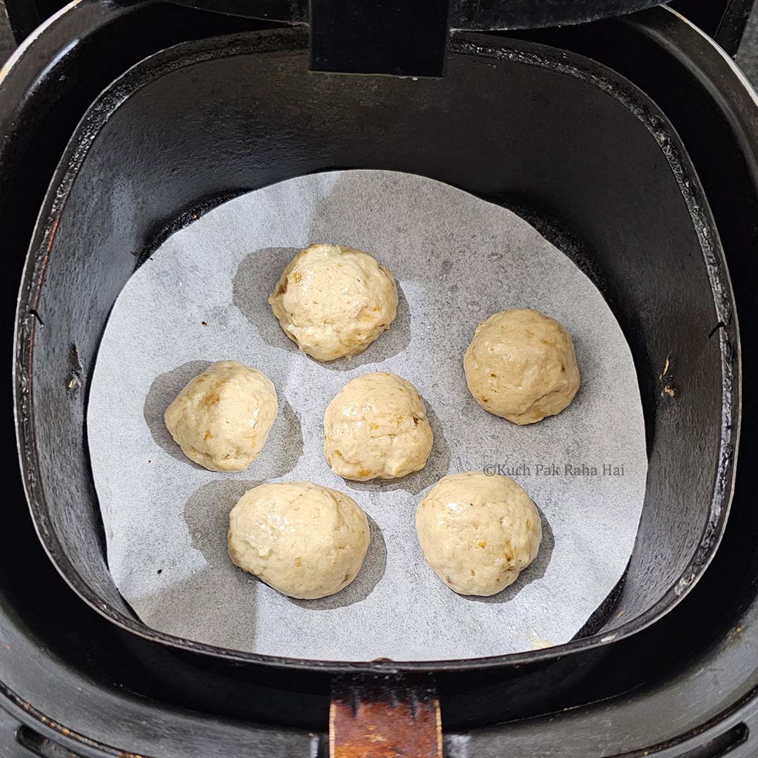 Placing banana donut holes in air fryer.