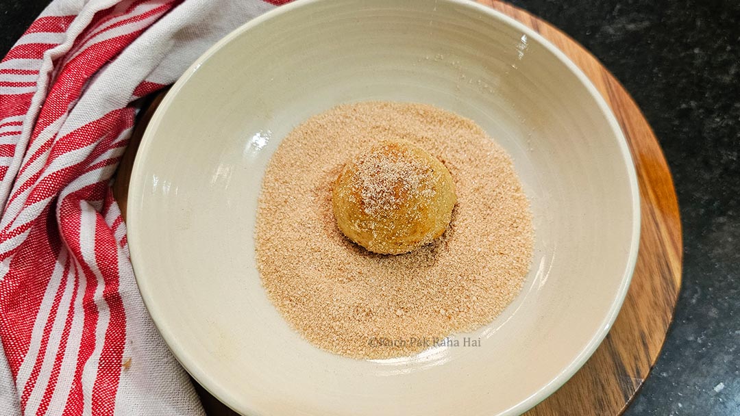 Tossing donut holes in mixture of cinnamon & sugar.