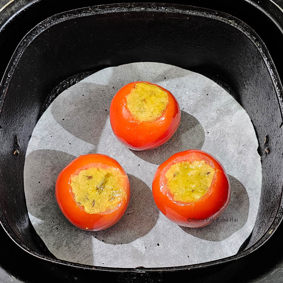 Stuffed tomatoes placed in air fryer basket.