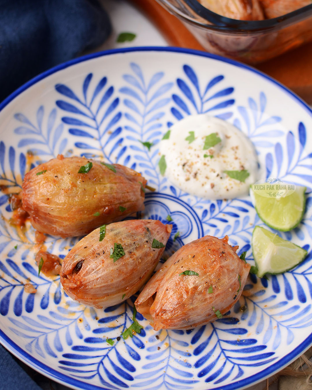 Stuffed onions in a plate served with greek yogurt dip and lemon wedges.