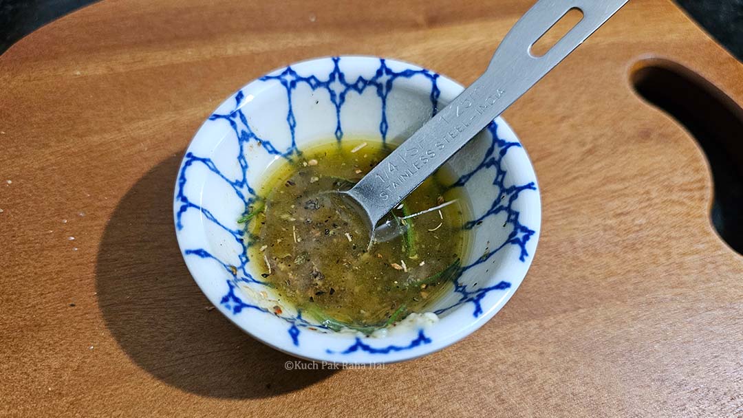 Mixing oil with herbs and spices in a bowl.