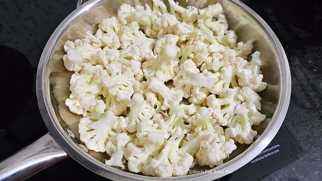 Adding chopped cauliflower in a pan.