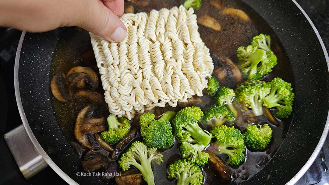 Adding ramen water & broccoli florets to mushrooms.