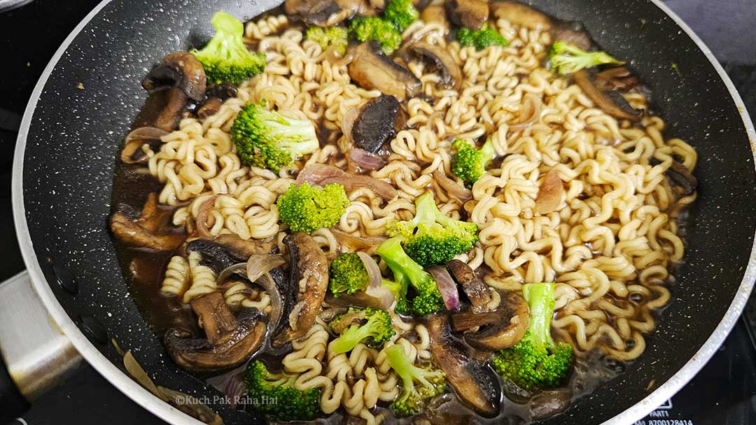 Stirring ramen to mix with broccoli mushrooms.