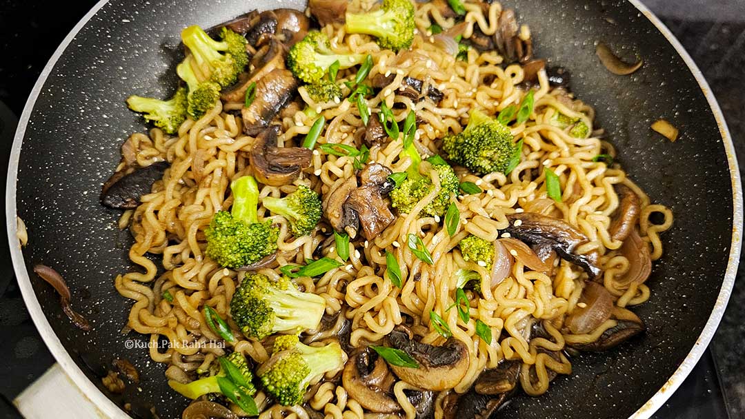 Garnishing broccoli mushrooms ramen with spring onion and sesame seeds.